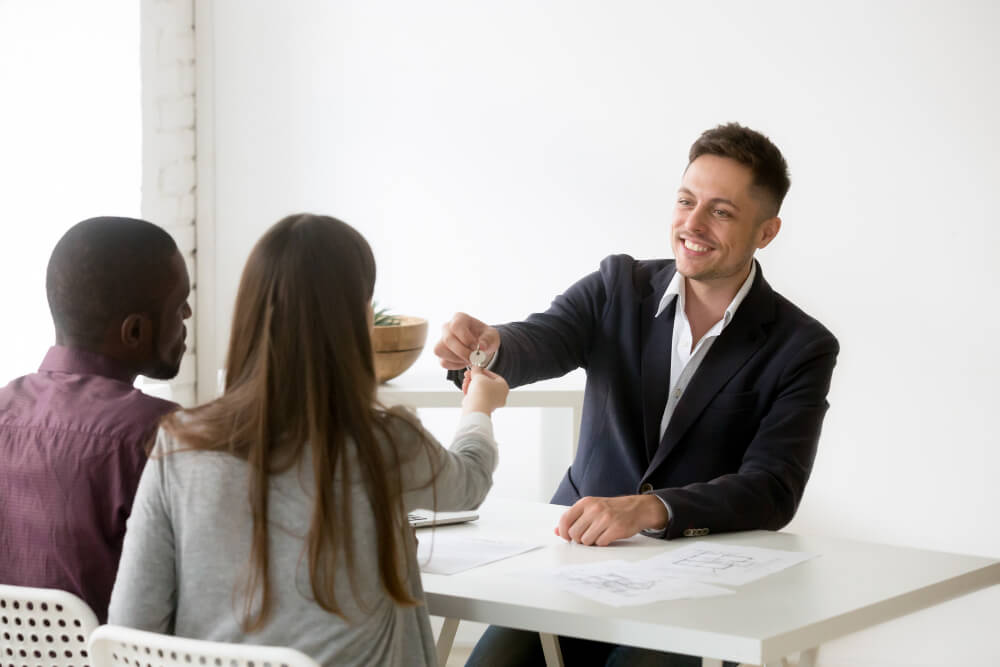 realtor handing over keys to couple